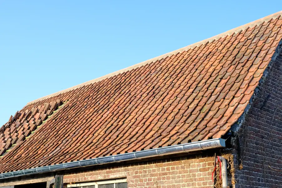 Het afgewerkte dak in Aalter met nieuwe pannen en een nieuwe zinken goot