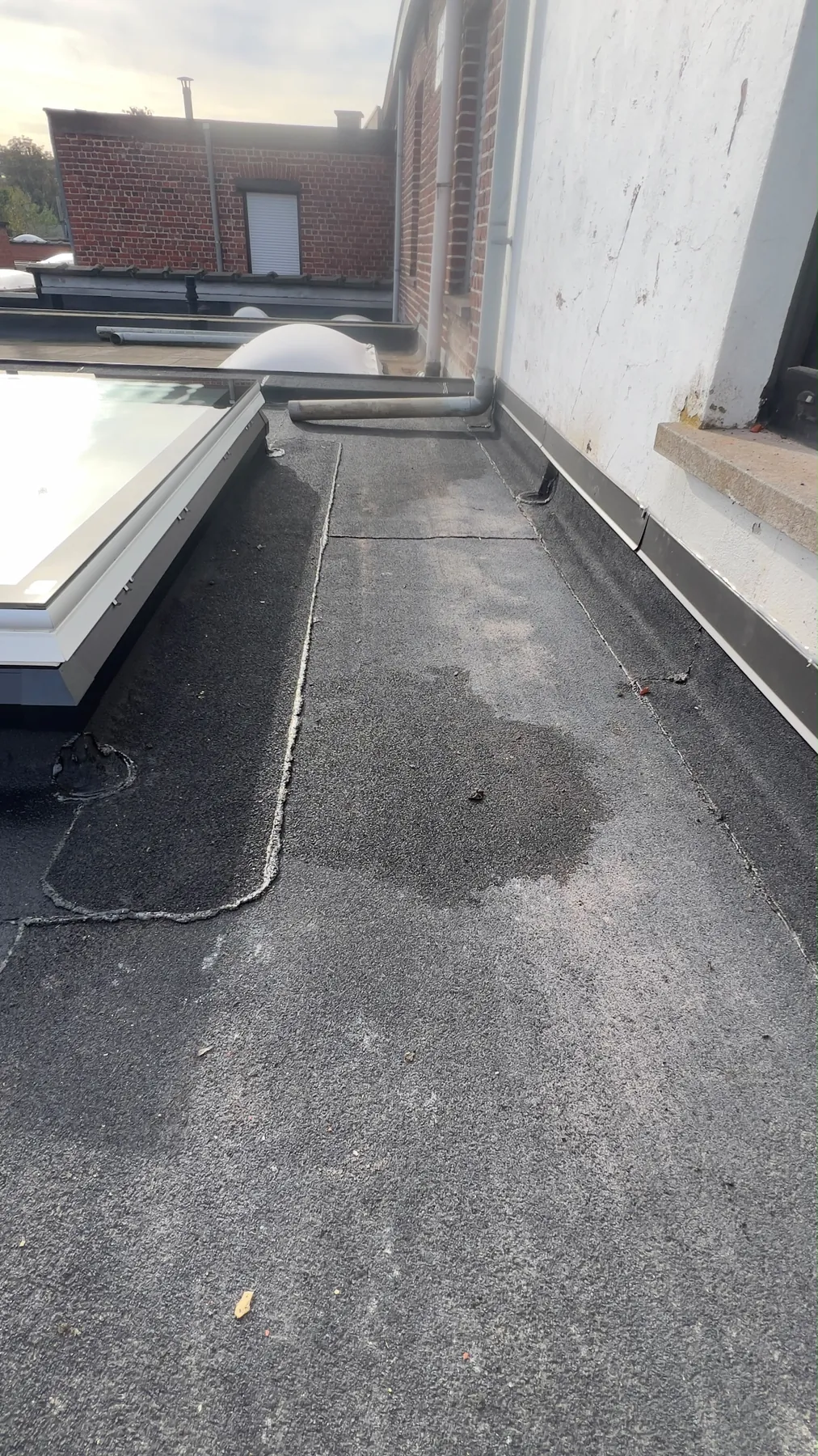 De roofing langs de gevel en het dakraam